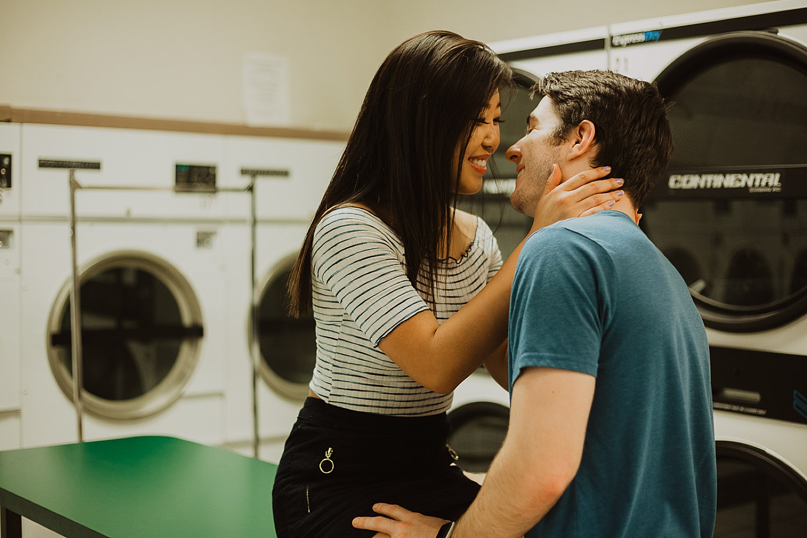 Cute Couple in Laundromat Embracing Engagement Photos taken by Kansas City Engagement Photographer, Caitlyn Cloud Photography