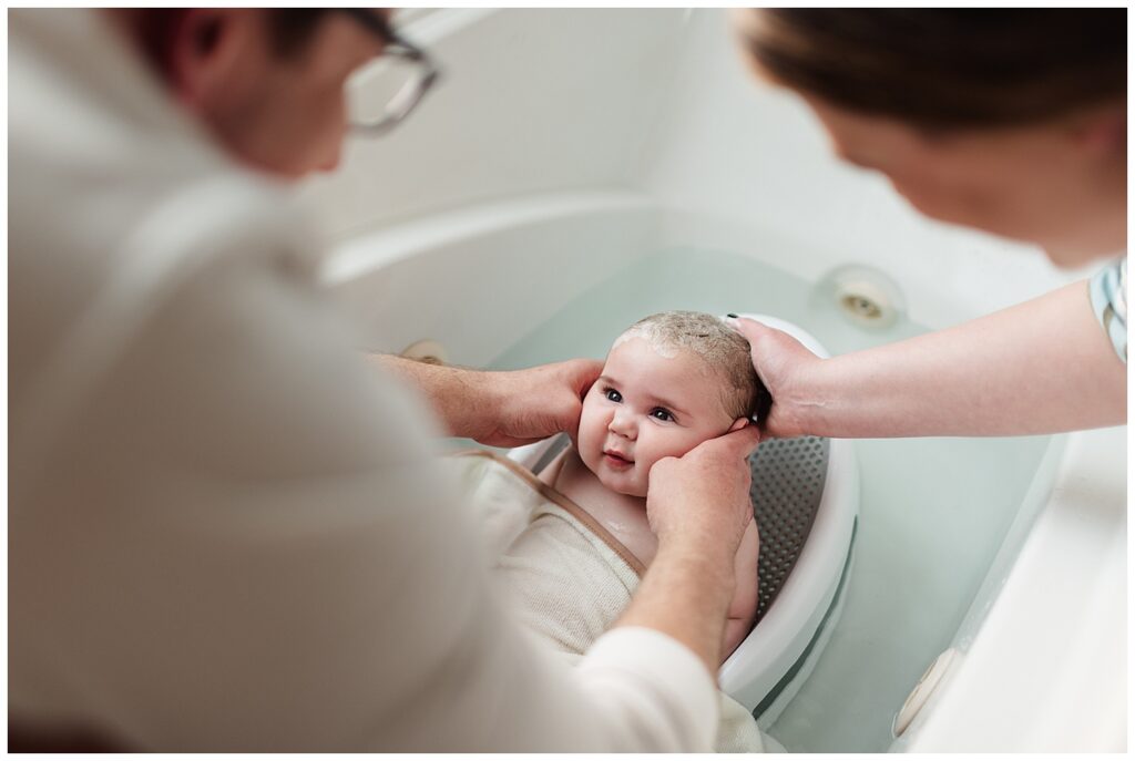 Mom and dad giving baby a bath during documentary family photos